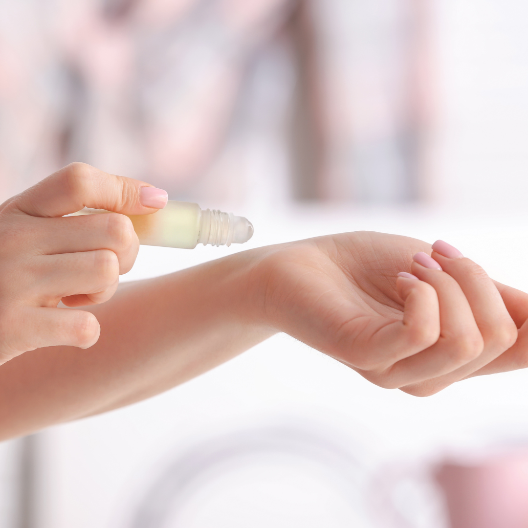 Person applying oil perfume to wrist